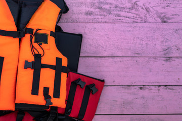 Top view of orange life jacket on pink wood background, copy space.