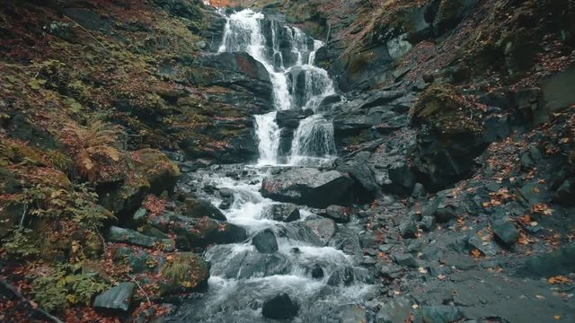 wonderful white foaming waterfall near stone tourist path with wooden handrails in autumn aerial view. Shipot waterfall, Carpathian mountains. 4K