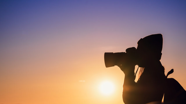 Young woman photographer taking photo with sunset on mountain natural background.