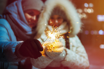 Woman and girl with christmas sparklers.