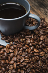 close up cup of coffee with beans on brown wooden background