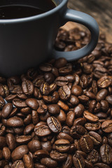 close up cup of coffee with beans on brown wooden background