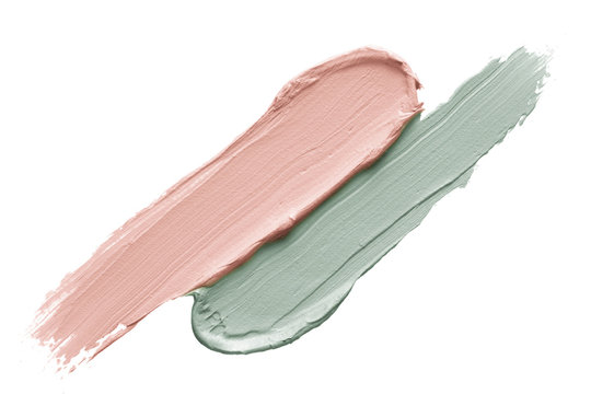 Color corrector strokes isolated on white background. Green and pink color correcting cream concealer smudge smear swatch sample. Makeup base creamy texture.