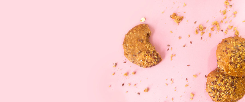 Galletas integrales de avena y semillas de ajonjoli sobre un fondo rosado