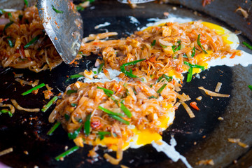 Chef cooking noodles and vegetables in a pan