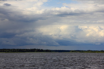 Dramatic sky clouds over lake, river stormy landscape