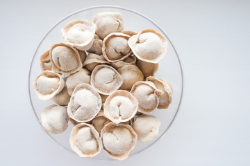 Traditional meat dumplings in a transparent plate after freezing for quick cooking. The national dish of Russian cuisine on a white background.