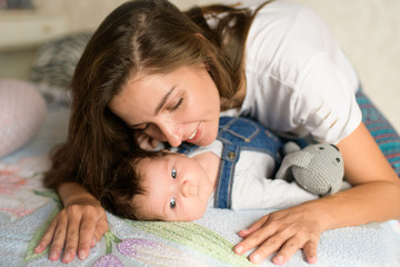 Mom with a child in bed. Happy loving family. Mother and her daughter child girl playing together.