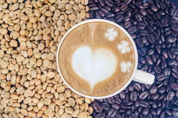 Raw coffee beans with hot latte art on open space.