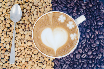 Raw coffee beans with hot latte art on open space.