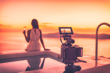 Videography behind the scene video camera shooting movie at sunset beach resort hotel filming actress woman acting, luxury travel. Professional videography equipment shooting outdoor at sunset. © Maridav