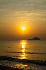 Fototapeta na wymiar The tropical sea, sunset, has an island in the back. Clear orange sky .
