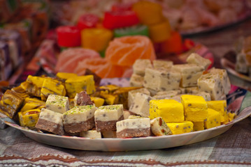 Fototapeta na wymiar Turkish national sweets are sold at the fair. Multi-colored Asian desserts stacked on the table. Rahat lokum in bulk is sold at the festival.