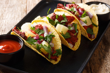 Tacos Al Pastor are thinly sliced pieces of marinated pork serve them up with some sliced onion, pineapple, and cilantro close-up on a plate. horizontal