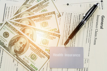 health insurance card and bank note and pen on background of general insurance claim form documents