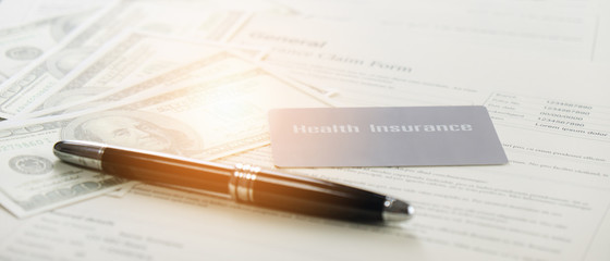 health insurance card and bank note and pen on background of general insurance claim form documents