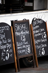 Menu and price boards propped up against mobile food trailer at weekly Saturday marketplace 