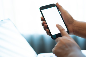 hand using a mobile phone with white blank screen over the laptop