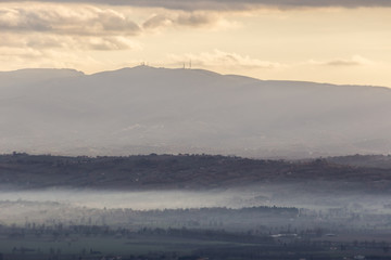 Mist filling a valley in Umbria (Italy) at sunet, with layers of mountains and hills and warm colours