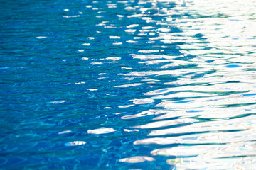 close up of abstract blue ripped and texture of water with sun light reflection in swimming pool. Selective and soft focus.