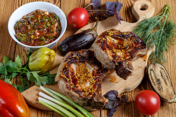 Grilled meat on the bone with vegetables, herbs and barbecue sauce.
