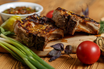Grilled meat on the bone with vegetables, herbs and barbecue sauce.