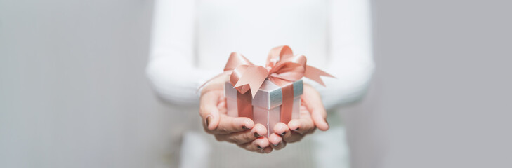 Woman hands with white sweater holding a small gift box for special event with copy space.