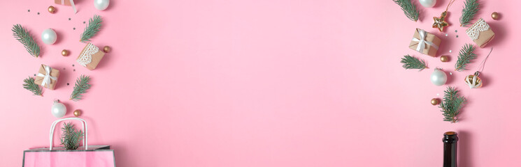 Champagne bottle and Package with different christmas decoration on pink background. New year concept.