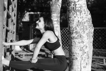 A beautiful sports girl in black sportswear is doing a warm-up at the stadium. The concept of a healthy lifestyle.