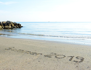 Text Sommer 2019 in den Sand geschrieben am Meer bei Sonnenaufgang