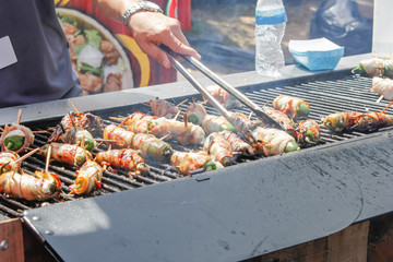 A person cooks Jalapeño poppers on a grill
