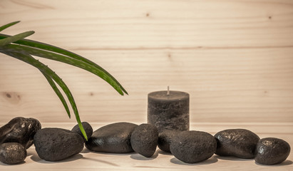 Obraz na płótnie Canvas Schwarze Sauna Steine mit Ayurveda Pflanze und Kerze