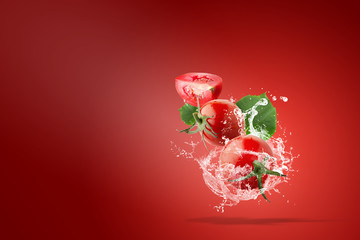 Water splashing on Fresh Red Tomatoes over red background
