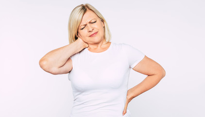 Upset blonde senior woman with strong back and neck pain