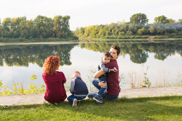 Childhood and nature concept - Family with little sons sitting on the green grass