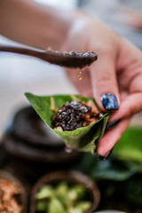 Thai Food Miang Kum Leaf-Wrapped Bite-Size Appetizer,A hand holdind a Leaf-Wrapped Bite-Size Appetizer. A Thai snack set of Wild Betel Leaf bush leave with ingredients chopped or cut into small pieces