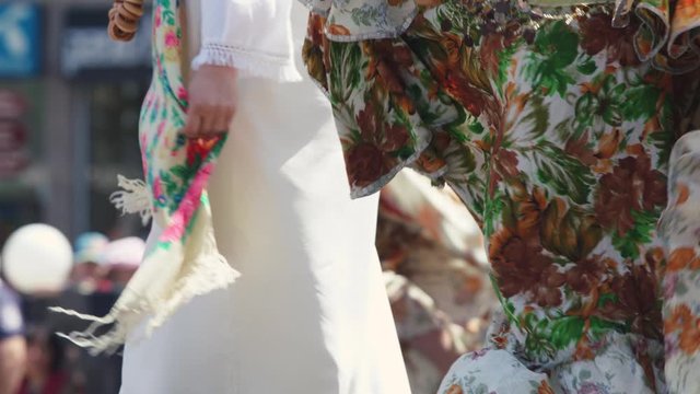 Women dance in the street during  bulgarian ethnic celebration in colorful skirts. Close-up. 