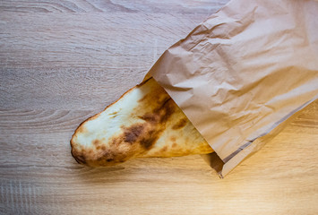 Georgian and Armenian lavash slightly burnt lying on the table in a gray paper bag..