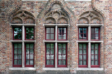 Old brick wall whith three windows with red frames