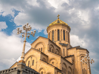Fototapeta premium The Holy Trinity Cathedral of Tbilisi against blue sky with clouds