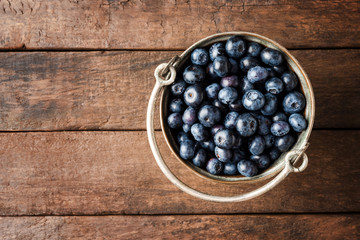 Fresh blueberries in rustic bowl on wooden table. Close up.