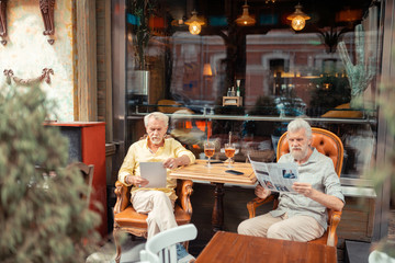 Two grey-haired retired men sitting outside the cafeteria