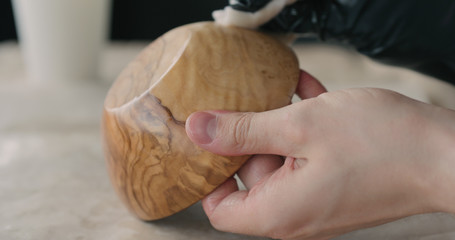 woodworker applying oil finish to olive wood bowl