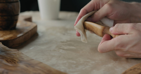 Obraz na płótnie Canvas woodworker applying oil finish to olive wood scoop