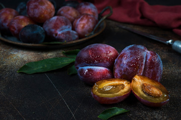 Still life of fresh seasonal plums with water droplets