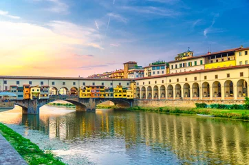 Wall murals Ponte Vecchio Ponte Vecchio bridge with colourful buildings houses over Arno River reflecting water and embankment promenade archways, historical centre of Florence city, blue evening sky clouds, Tuscany, Italy