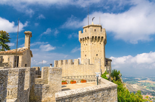 Republic San Marino Seconda Torre La Cesta second fortress tower with merlons and brick walls on Mount Titano stone rock, blue sky white clouds background