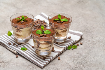 Classic tiramisu dessert in a glass on kitchen towel on concrete background