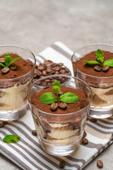 Classic tiramisu dessert in a glass on kitchen towel on concrete background