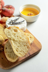 Top view different types of cheeses on wooden cutting board. Cheese with fig peach, honey, ciabatta and nuts, glass of red wine. Stylish food flat lay on grey background. Copy space. Soft focus